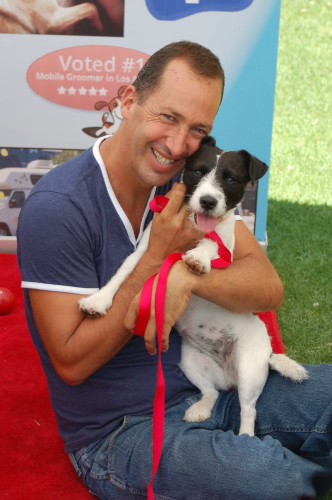 Chuck holds a black and white dog on the red carpet.
