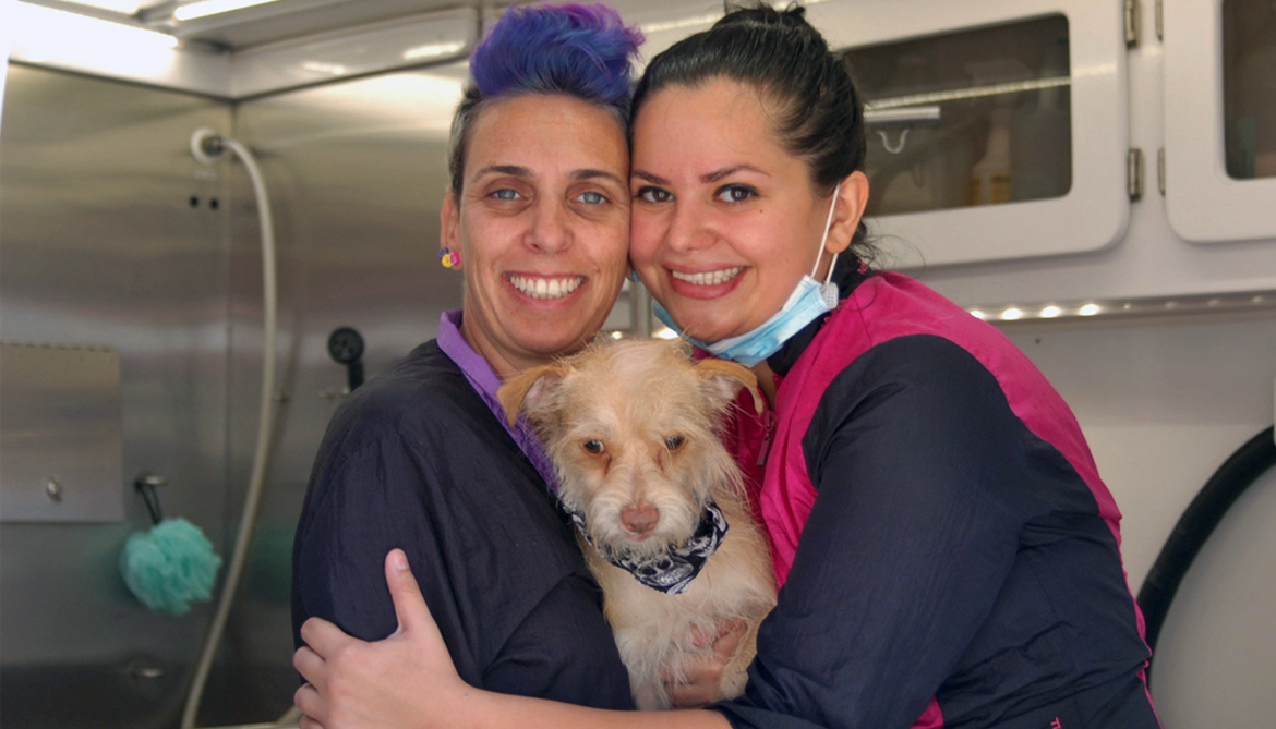 Yael and Amy holding a dog who has just been groomed.