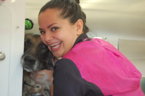 Animal Groomer Amy hugs a dog at a Grooming Station.