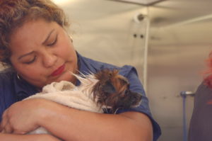 Dog Groomer Sarita hugs a dog at a Grooming Station.