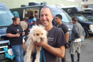 Chuck holds a fluffy dog at a community event.