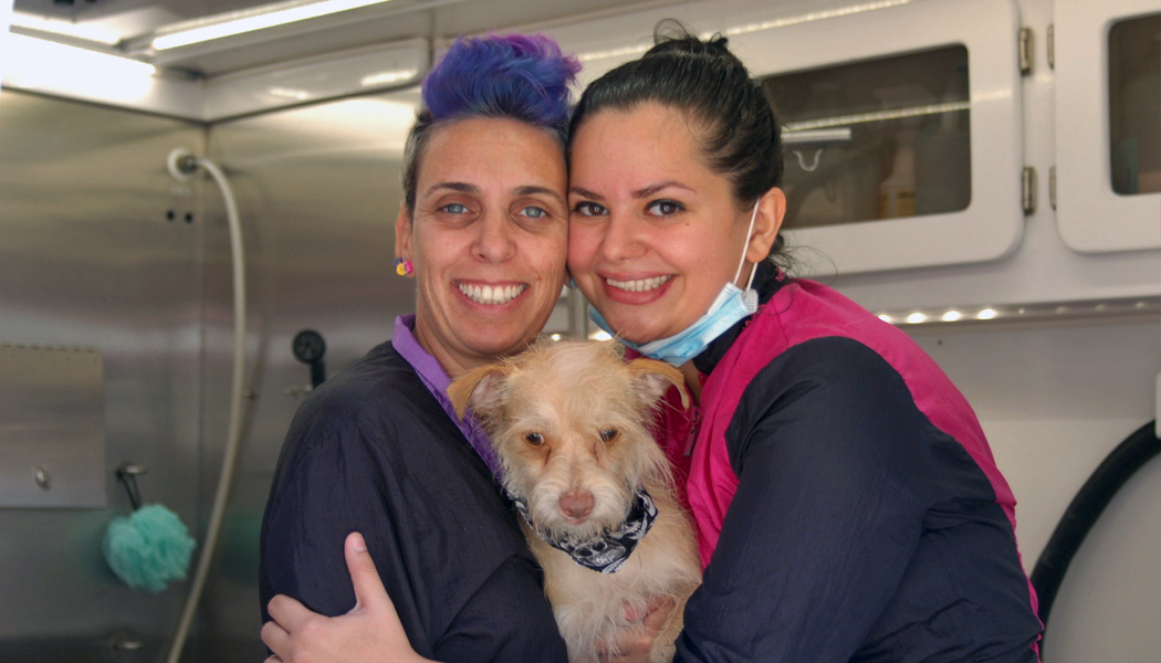 Yael and Amy holding a dog who has just been groomed.