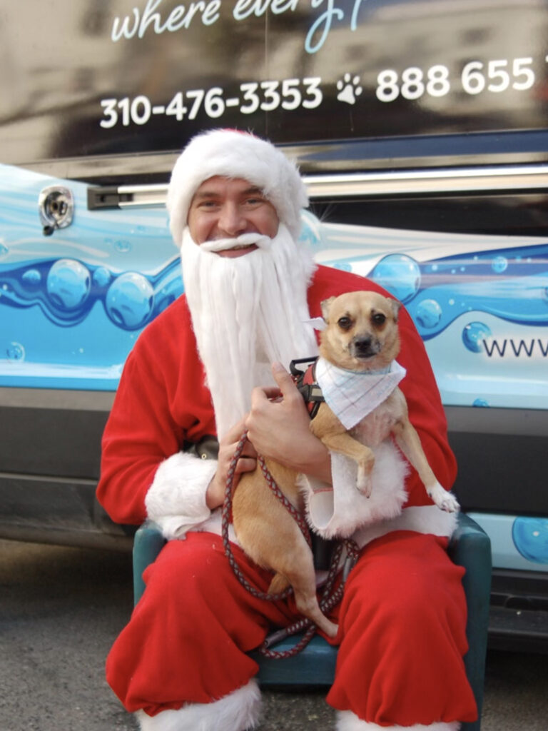 Santa with an adorable dog wearing a Christmas bow.